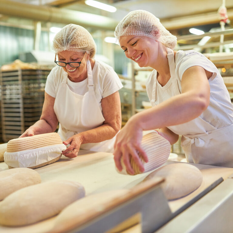 Baker apprentice with boss baking bread