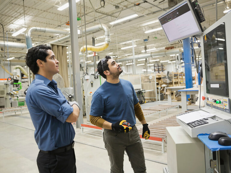 Production planning manufacturing environment - workers looking at screen in warehouse